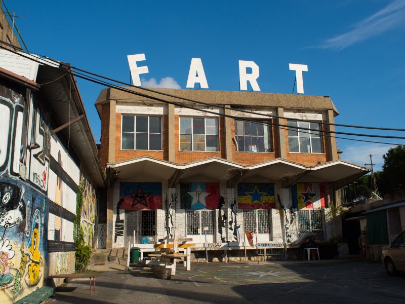 An old factory building, on the roof spelling the word fart in big letters